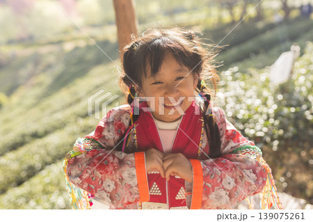 Joyful young girl in traditional ethnic clothing smiles brightly outdoors Joyful young girl in traditional ethnic clothing smiles brightly outdoors 139075261