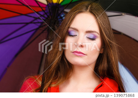 Woman standing under multicolored umbrella Woman standing under multicolored umbrella 139075868