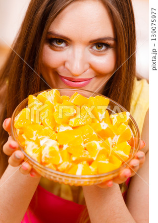 Woman holds bowl full of sliced orange fruits Woman holds bowl full of sliced orange fruits 139075977