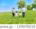 青空の草原を手を繫いで歩く家族 139076018