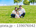 青空の草原に座る家族 139076042