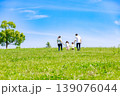 青空の草原を手を繫いで歩く家族 139076044