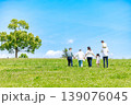 青空の草原を散歩する三世代家族 139076045