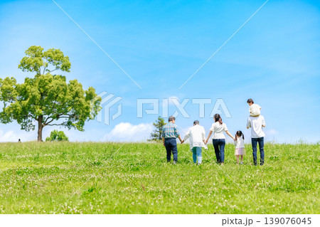 青空の草原を散歩する三世代家族 139076045