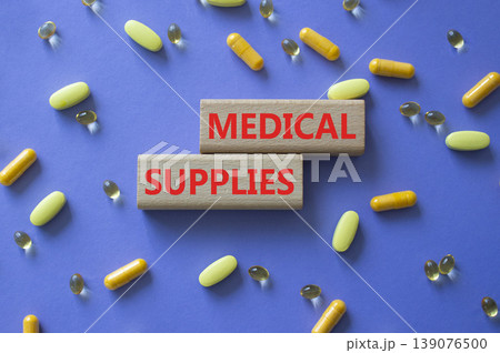 Medical supplies symbol. Concept word Medical supplies on wooden blocks. Beautiful purple background with pills. Medicine and Medical supplies. Copy space 139076500