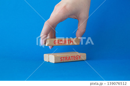 Growth strategy symbol. Concept word Growth strategy on wooden blocks. Businessman hand. Beautiful blue background. Business and Growth strategy concept. Copy space Growth strategy symbol. Concept word Growth strategy on wooden blocks. Businessman hand. Beautiful blue background. Business and Growth strategy concept. Copy space 139076512