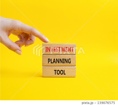 Investment planning tool symbol. Concept word Investment planning tool on wooden blocks. Businessman hand. Beautiful yellow background. Business and Investment planning tool. Copy space Investment planning tool symbol. Concept word Investment planning tool on wooden blocks. Businessman hand. Beautiful yellow background. Business and Investment planning tool. Copy space 139076575