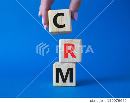 CRM - Customer relationship management symbol. Concept word CRM on wooden cubes. Businessman hand. Beautiful blue background. Business and CRM concept. Copy space. 139076652