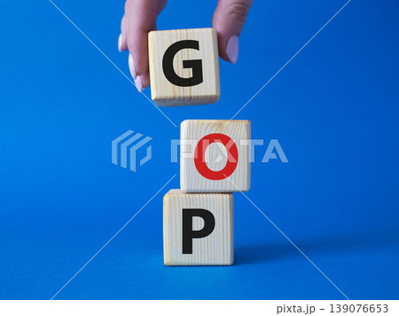 GOP - Gross Operating Profit symbol. Concept word GOP on wooden cubes. Businessman hand. Beautiful blue background. Business and GOP concept. Copy space. GOP - Gross Operating Profit symbol. Concept word GOP on wooden cubes. Businessman hand. Beautiful blue background. Business and GOP concept. Copy space. 139076653