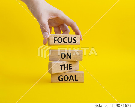 GOAL symbol. Wooden blocks with words FOCUS ON THE GOAL. Businessman hand. Beautiful yellow background. Business and GOAL concept. Copy space GOAL symbol. Wooden blocks with words FOCUS ON THE GOAL. Businessman hand. Beautiful yellow background. Business and GOAL concept. Copy space 139076673