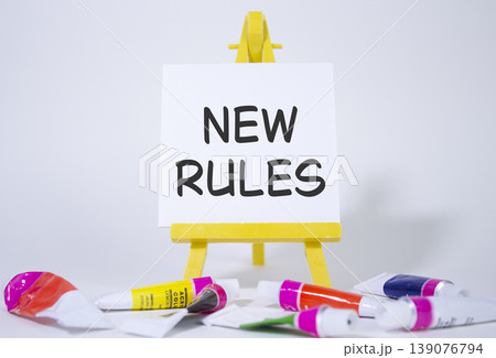 New rules symbol. Concept word Manage stress on wooden blocks. Beautiful yellow background with paints and easel. Business and New rules concept. Copy space New rules symbol. Concept word Manage stress on wooden blocks. Beautiful yellow background with paints and easel. Business and New rules concept. Copy space 139076794