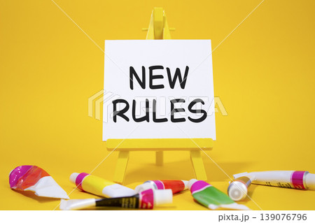New rules symbol. Concept word Manage stress on wooden blocks. Beautiful yellow background with paints and easel. Business and New rules concept. Copy space New rules symbol. Concept word Manage stress on wooden blocks. Beautiful yellow background with paints and easel. Business and New rules concept. Copy space 139076796