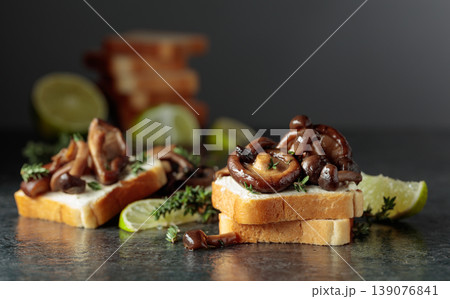 Sandwiches with cream cheese, shiitake and shimeji mushrooms, lime wedges and sprigs of thyme. Sandwiches with cream cheese, shiitake and shimeji mushrooms, lime wedges and sprigs of thyme. 139076841