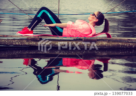 Girl training in sporty clothes on lake shore Girl training in sporty clothes on lake shore 139077033