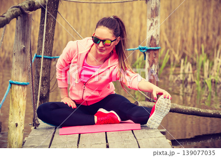 Girl training in sporty clothes on lake shore Girl training in sporty clothes on lake shore 139077035