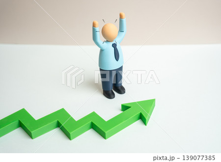An office worker rejoices at a green growth arrow. Sales salaries and bonuses rise. Economic improvement supports motivation and positive business performance. An office worker rejoices at a green growth arrow. Sales salaries and bonuses rise. Economic improvement supports motivation and positive business performance. 139077385