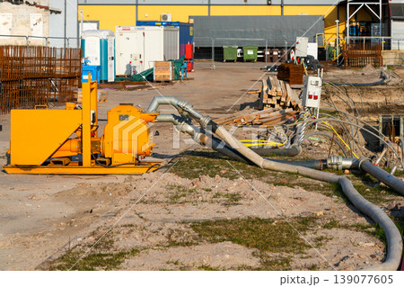 Industrial dewatering pump and hose system operating at construction site excavation for drainage Industrial dewatering pump and hose system operating at construction site excavation for drainage 139077605