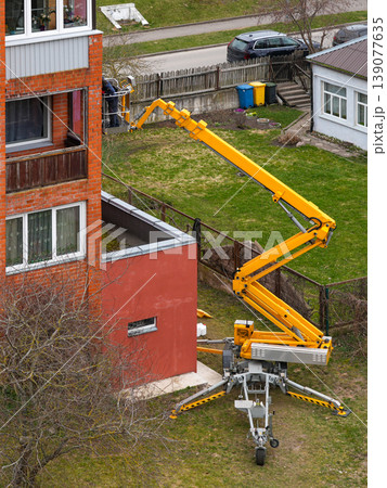 Worker on boom lift servicing apartment building facade with cherry picker in residential area Worker on boom lift servicing apartment building facade with cherry picker in residential area 139077635