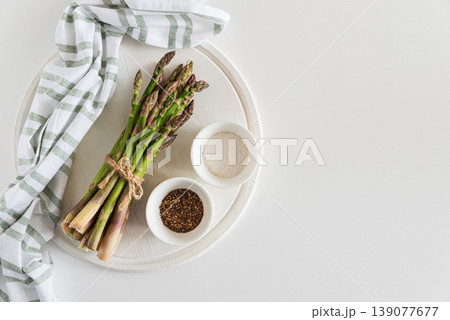 Bundle of fresh asparagus tied with twine on round white wooden tray Bundle of fresh asparagus tied with twine on round white wooden tray 139077677