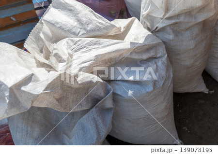 Bags of material are piled together in a warehouse. The setting shows an organized area for storage. The scene takes place during the day Bags of material are piled together in a warehouse. The setting shows an organized area for storage. The scene takes place during the day 139078195