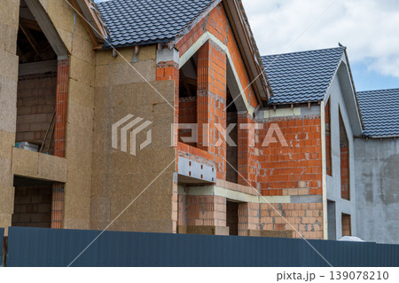 Workers are constructing new homes using brick and block materials in a city location under a cloudy sky Workers are constructing new homes using brick and block materials in a city location under a cloudy sky 139078210