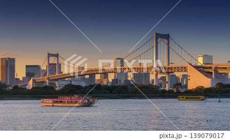 Tokyo, Japan - Oct 13 2024, panoramic view of Tokyo Bay with a cable-stayed Rainbow Bridge above it, a boat and a water bus sailing, at sunset, Tokyo, Japan 139079017