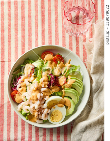 Healthy shrimp avocado salad bowl with egg and dressing on striped background Healthy shrimp avocado salad bowl with egg and dressing on striped background 139079022