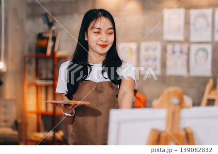 Female artist wears black hat posing near picture indoor the studio Female artist wears black hat posing near picture indoor the studio 139082832