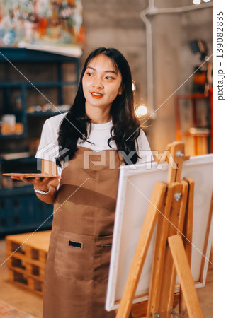 Female artist wears black hat posing near picture indoor the studio Female artist wears black hat posing near picture indoor the studio 139082835