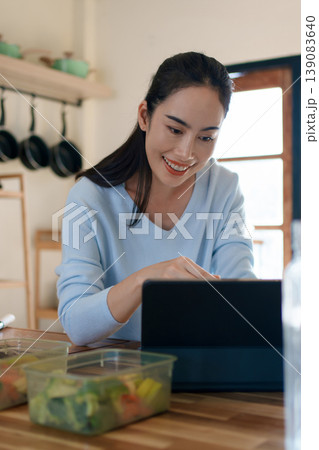 Woman using tablet to follow healthy cooking recipe while preparing fresh meal at home kitchen Woman using tablet to follow healthy cooking recipe while preparing fresh meal at home kitchen 139083640
