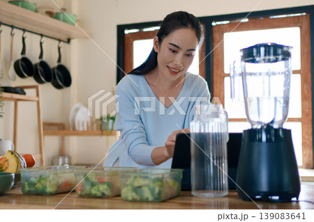 Woman using tablet to follow healthy cooking recipe while preparing fresh meal at home kitchen Woman using tablet to follow healthy cooking recipe while preparing fresh meal at home kitchen 139083641