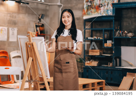 Female artist wears black hat posing near picture indoor the studio Female artist wears black hat posing near picture indoor the studio 139084195
