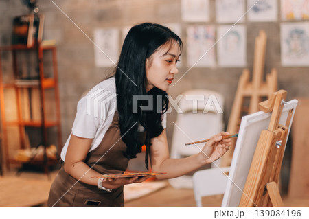 Female artist wears black hat posing near picture indoor the studio Female artist wears black hat posing near picture indoor the studio 139084196