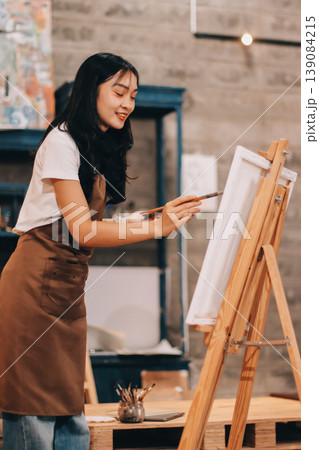 Female artist wears black hat posing near picture indoor the studio 139084215