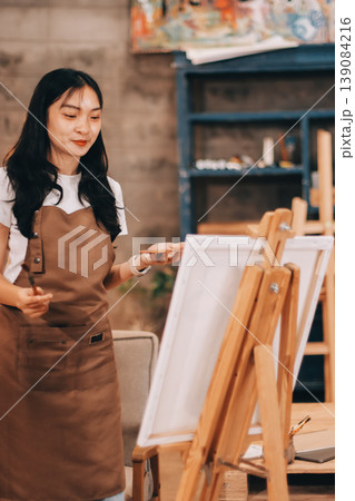Female artist wears black hat posing near picture indoor the studio Female artist wears black hat posing near picture indoor the studio 139084216