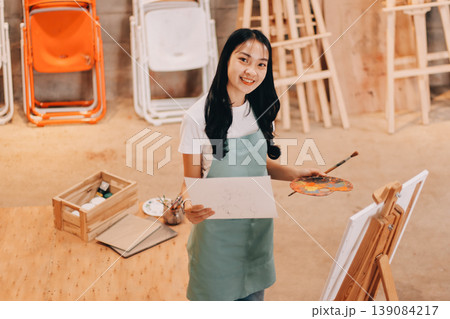 Female artist wears black hat posing near picture indoor the studio Female artist wears black hat posing near picture indoor the studio 139084217