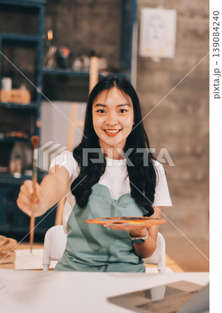 Female artist wears black hat posing near picture indoor the studio Female artist wears black hat posing near picture indoor the studio 139084240