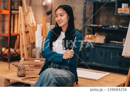 Female artist wears black hat posing near picture indoor the studio Female artist wears black hat posing near picture indoor the studio 139084256