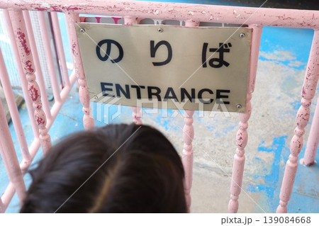 遊園地の乗り場入口の先頭で順番を待つ子供と「のりば」の二か国語看板 遊園地の乗り場入口の先頭で順番を待つ子供と「のりば」の二か国語看板 139084668