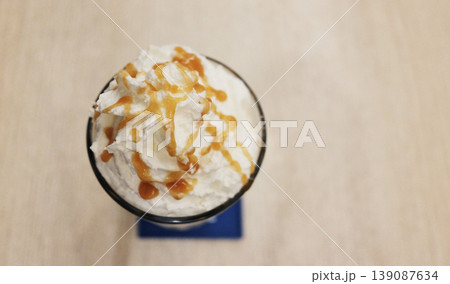 Iced latte coffee with whipped cream topped with caramel on a table in a traditional Thai cafe shop. Top view with copy space Iced latte coffee with whipped cream topped with caramel on a table in a traditional Thai cafe shop. Top view with copy space 139087634