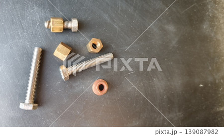 Various metallic fasteners and components are arranged on a gray surface Various metallic fasteners and components are arranged on a gray surface 139087982
