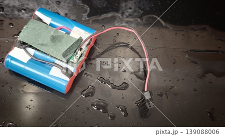 Battery pack placed on a wet surface with visible wires and connections Battery pack placed on a wet surface with visible wires and connections 139088006