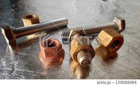 Different types of metal bolts and nuts on a shiny surface in a workshop 139088064