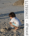Child squatting on sandy beach playing and exploring textures during peaceful seaside afternoon 139088275