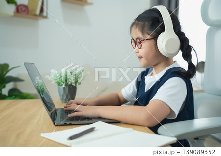 Young girl in home office wearing headphones, focused on laptop screen, studying or learning in cozy and modern interior space, educational environment Young girl in home office wearing headphones, focused on laptop screen, studying or learning in cozy and modern interior space, educational environment 139089352