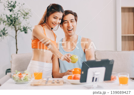 A happy couple prepares fresh vegetables, laughing and enjoying cooking a healthy meal together. 139089427