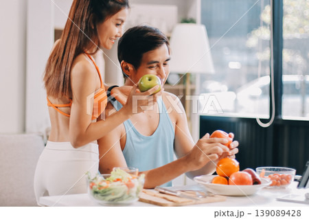 A happy couple prepares fresh vegetables, laughing and enjoying cooking a healthy meal together. 139089428