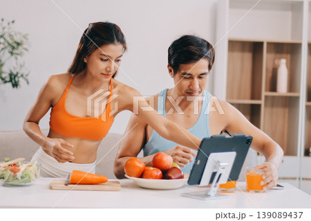 A happy couple prepares fresh vegetables, laughing and enjoying cooking a healthy meal together. 139089437