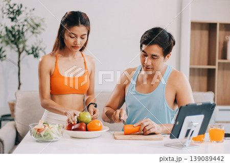A happy couple prepares fresh vegetables, laughing and enjoying cooking a healthy meal together. 139089442