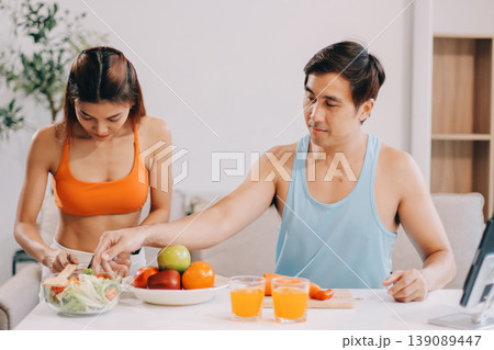 A happy couple prepares fresh vegetables, laughing and enjoying cooking a healthy meal together. A happy couple prepares fresh vegetables, laughing and enjoying cooking a healthy meal together. 139089447